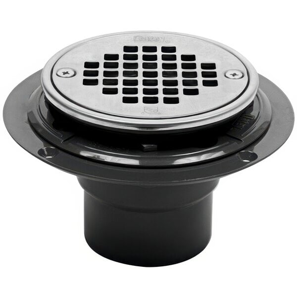 An Oatey PVC shower drain with a round metal strainer cover.