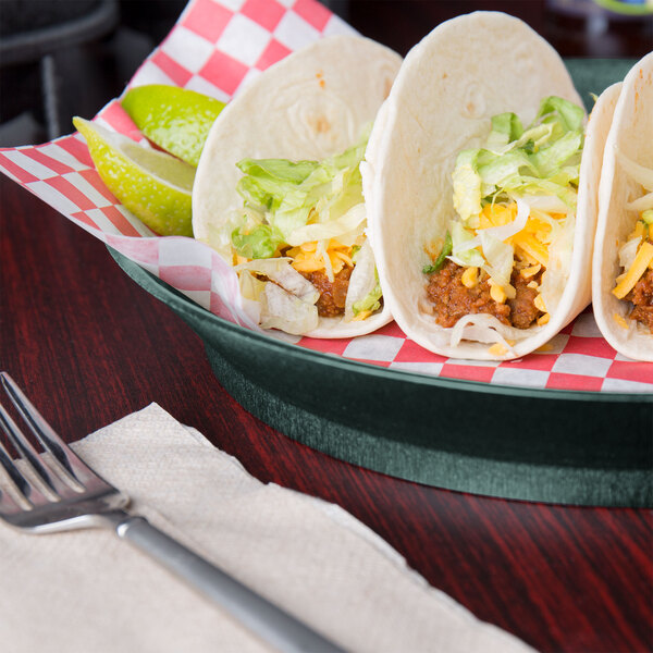 A round yellow and white polypropylene server with jalapenos on a table with a plate of tacos, a fork, and a lime.