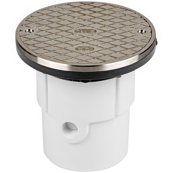 A white plastic pipe with a round metal drain cover with a black base.