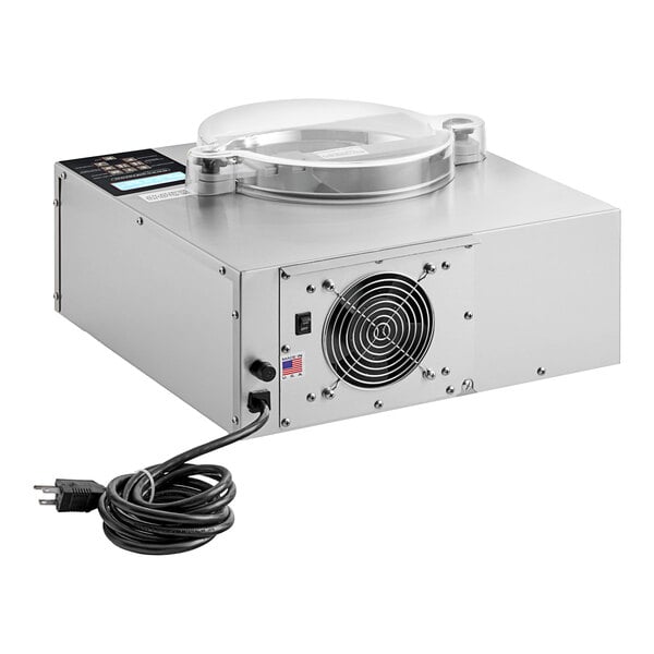 A silver ChocoVision Revolation V chocolate tempering machine on a counter with a black cord.