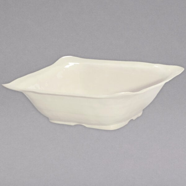 A white square bowl with a handle on a white surface.