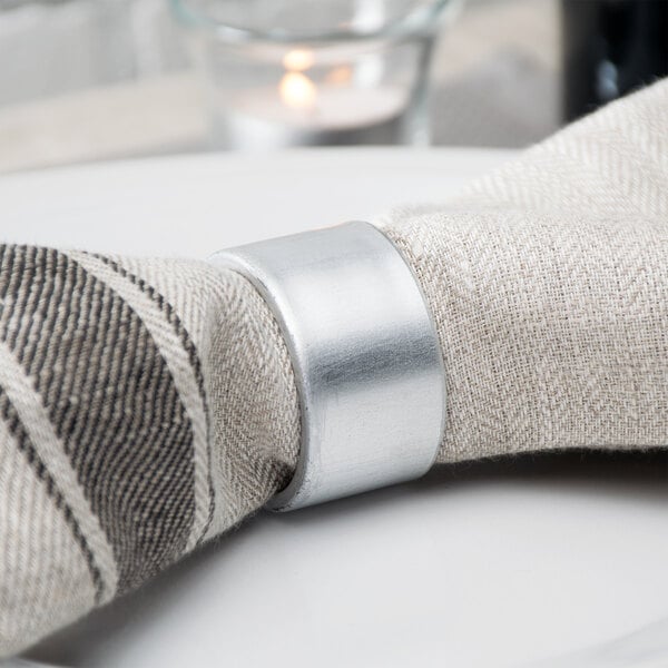 A Tabletop Classics by Walco silver polypropylene napkin ring on a napkin.