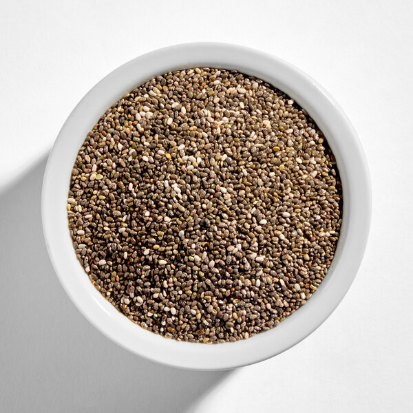 A white bowl filled with organic whole chia seeds.