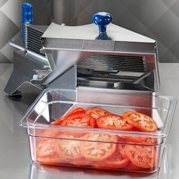 An Edlund tomato slicer on a counter next to a container of tomatoes.