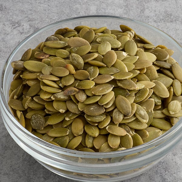 A bowl of Bob's Red Mill Organic Raw Pumpkin Seeds on a table.