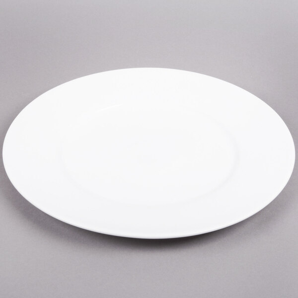 An Arcoroc white porcelain service plate with a white rim on a gray surface.