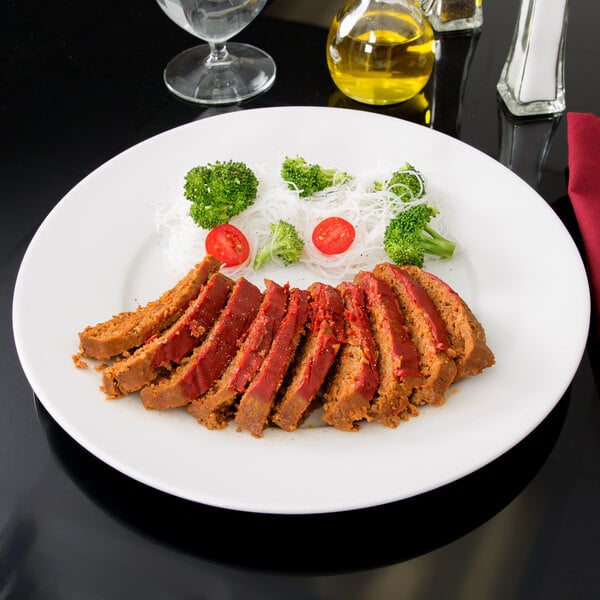 A white Arcoroc porcelain service plate with meat and vegetables on it.