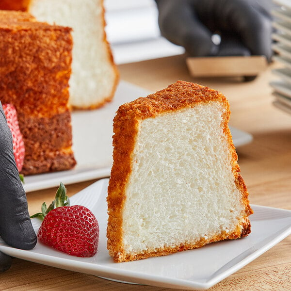 A slice of Krusteaz angel food cake on a plate with a strawberry.