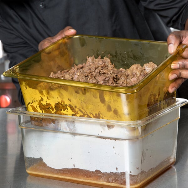 A person holding a yellow Cambro colander pan filled with food.