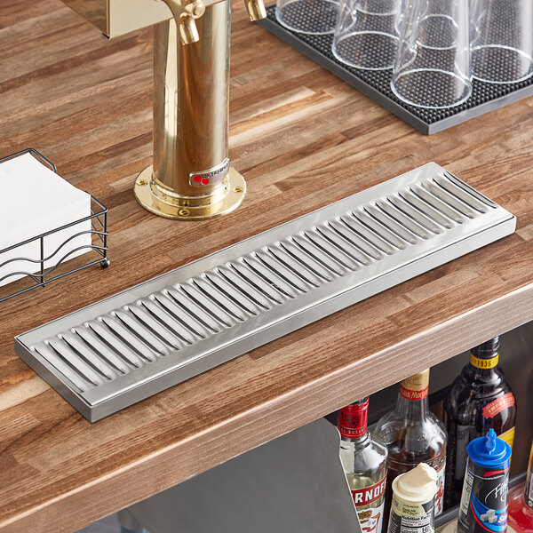 A Regency stainless steel surface-mount beer drip tray on a bar counter.