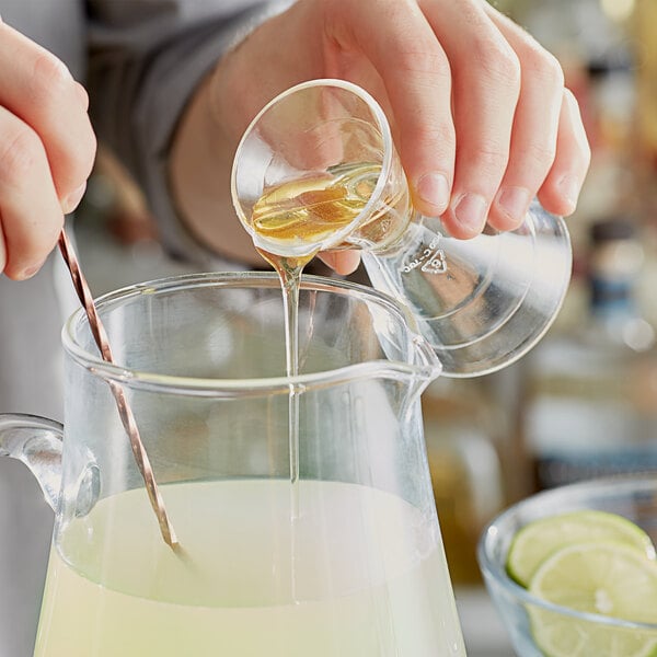 Bartender pouring agave into a pitcher of margaritas
