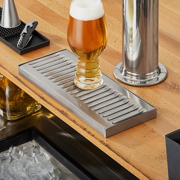 A glass of beer on a Regency stainless steel beer drip tray.