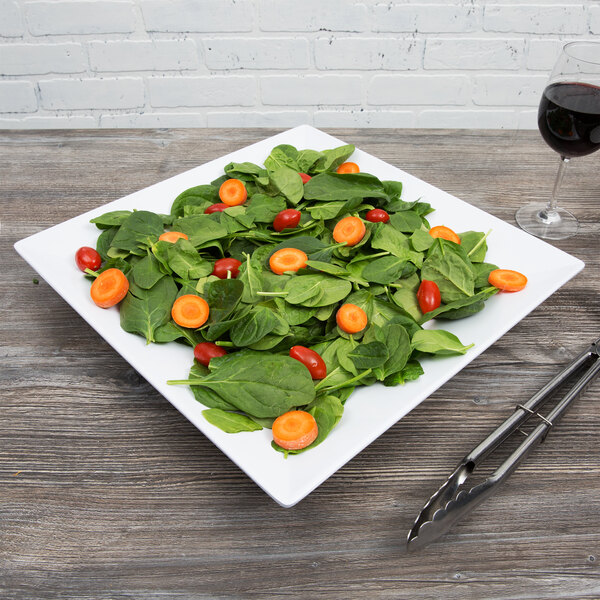 A white Siciliano square plate with a salad and a glass of wine.