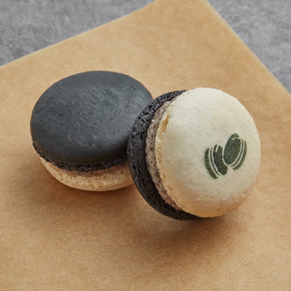 Two Macarons with black and white designs on a table.