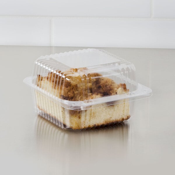 A Dart clear plastic square container with cake inside.