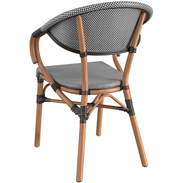 A Lancaster Table & Seating black and white wicker arm chair with a wooden frame and black and white seat.