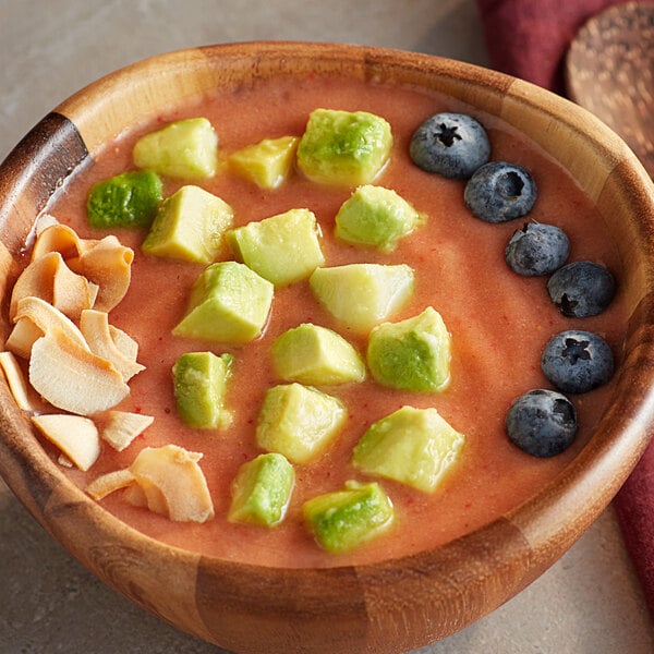 A bowl of frozen fruit with yellow and green cubes.