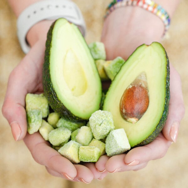 Two hands holding two halves of a Pitaya Foods avocado.