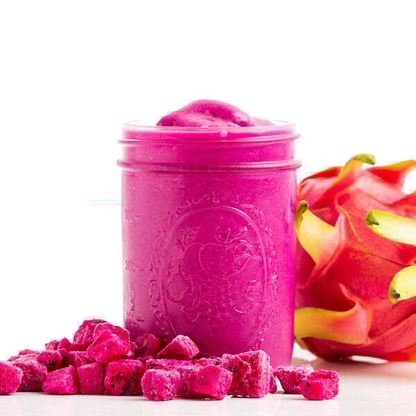A jar of pink smoothie with Pitaya Foods Organic Dragon Fruit cubes on top.