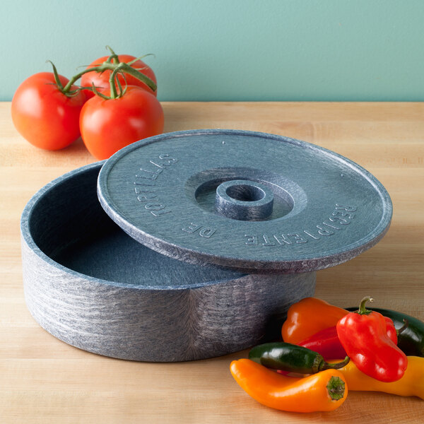 A round blue HS Inc. polyethylene container with a lid open next to tomatoes.