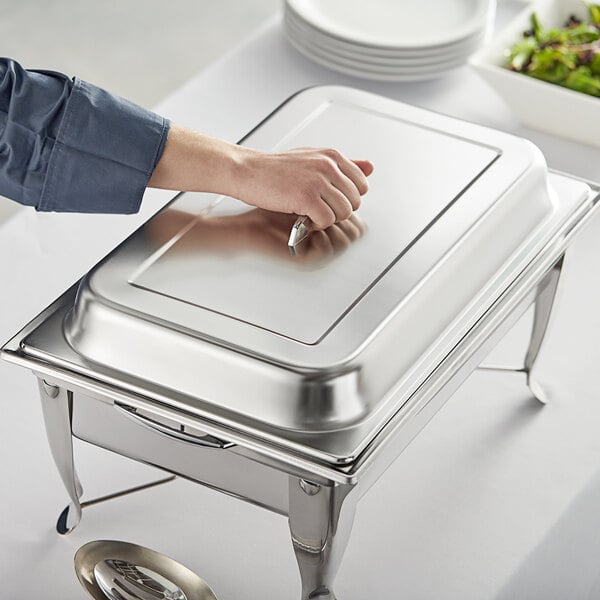 A person holding a silver Choice chafer with a plate of food.