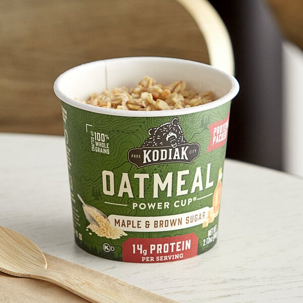 A green container of Kodiak Cakes Maple and Brown Sugar Oatmeal on a table.