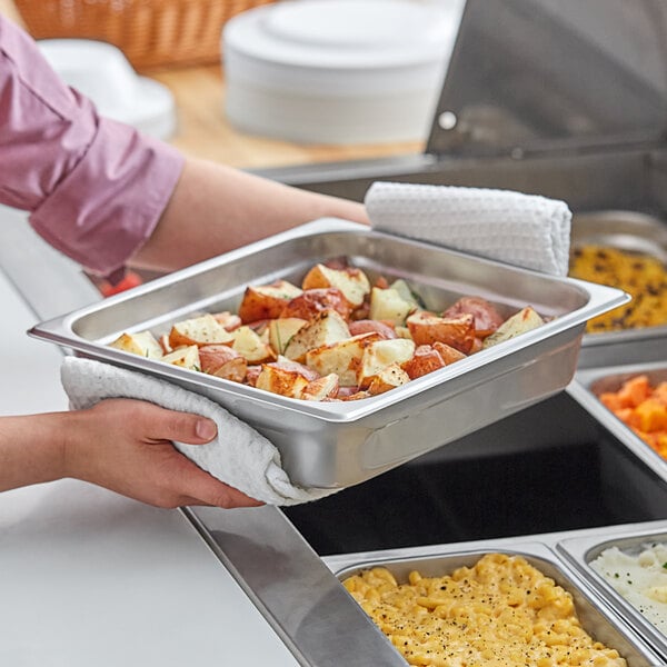 A person holding a Choice Economy chafer food pan filled with food.