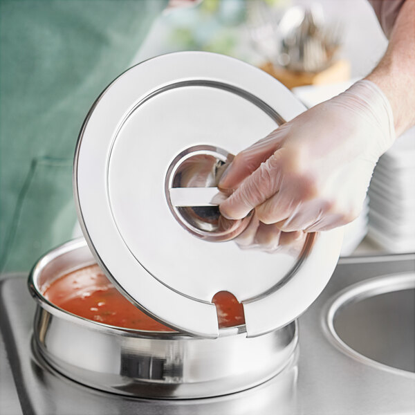 A person in gloves holding a Choice Deluxe Soup Marmite chafer cover over a pot.