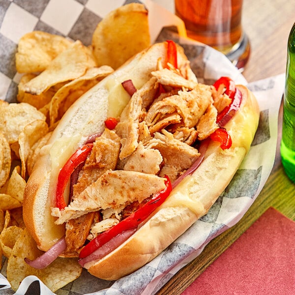 A plate with a sandwich made with Original Philly Cheesesteak Co. Marinated Chicken Steaks and vegetables.