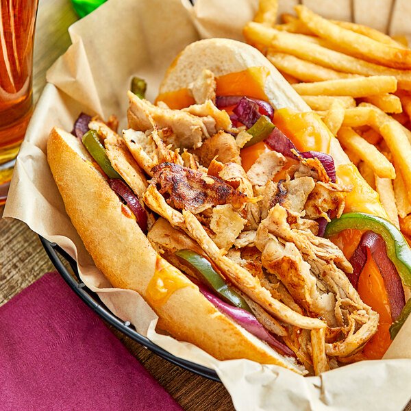 A plate with a sandwich made with Original Philly Cheesesteak Co. Marinated Chicken Sandwich Steaks and fries.