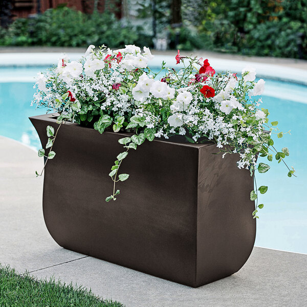 A Mayne Valencia espresso trough planter with flowers on an outdoor patio table.