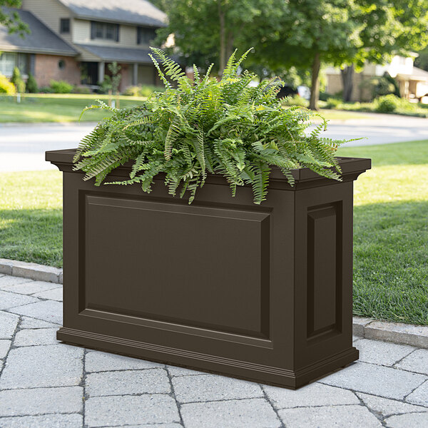 An espresso Mayne Nantucket trough planter on an outdoor table with plants in it.