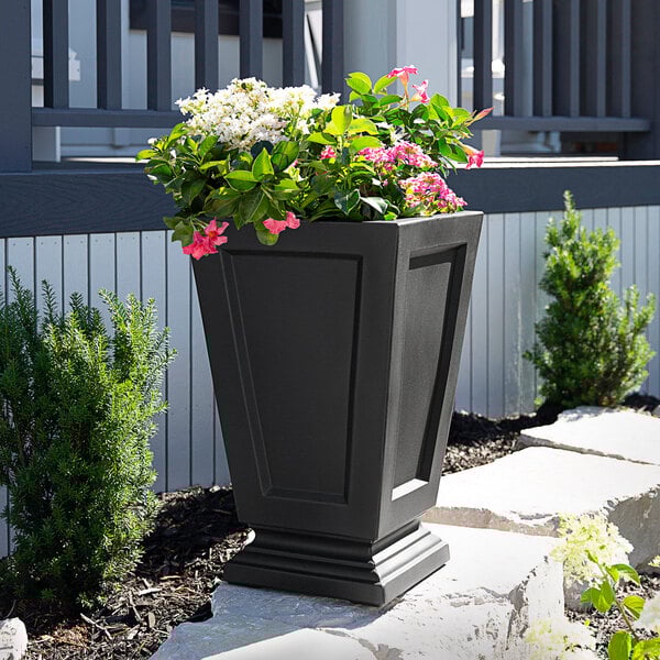 A black Mayne Aberdeen planter with pink flowers.