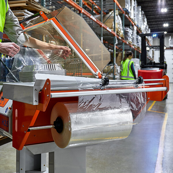 A person in a green vest using a Lavex Pro machine to pack plastic bags with Lavex Pro perforated shrink film.