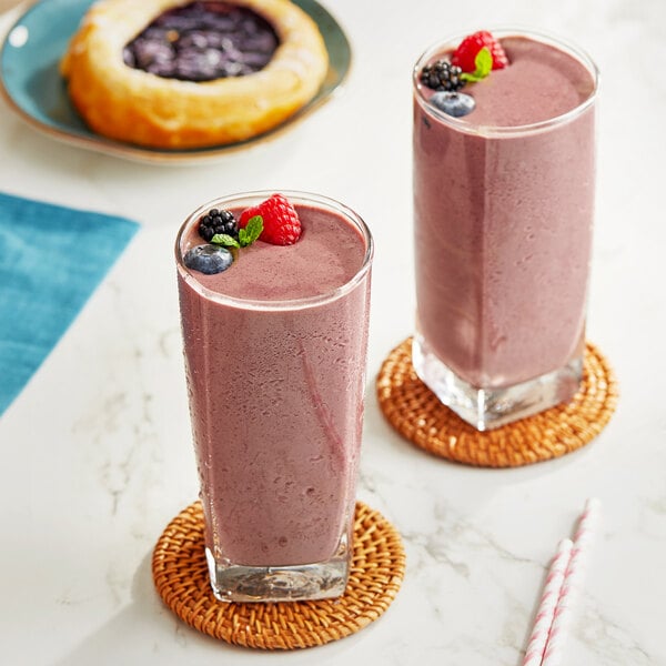 Two glasses of pink smoothies with Sambazon Acai and berries on top.