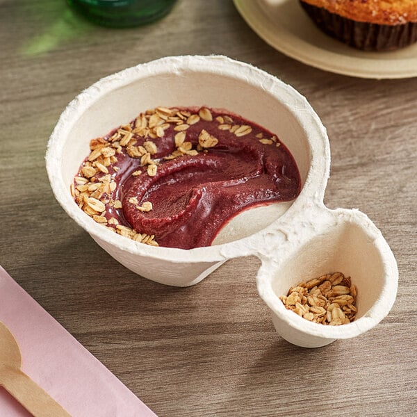 A bowl of oatmeal with red liquid and oat flakes with a wooden spoon.