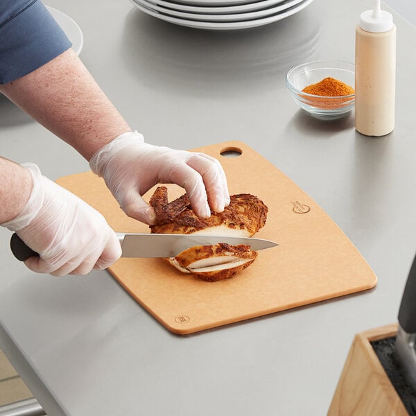 A person cutting a sandwich on a Mercer composite cutting board.