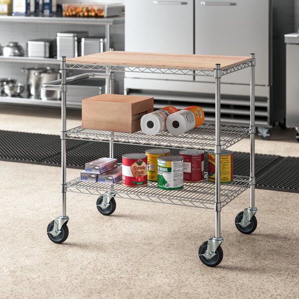 A metal Regency utility cart with food and drinks on wooden shelves.