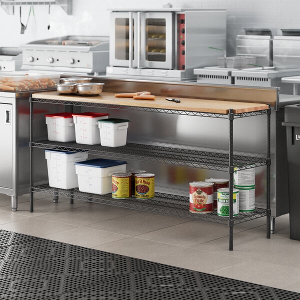 A kitchen with a counter and metal shelves holding white and red containers.