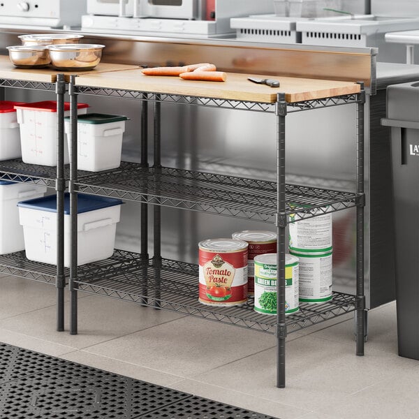 A black Regency metal shelf with wooden inserts holding food.