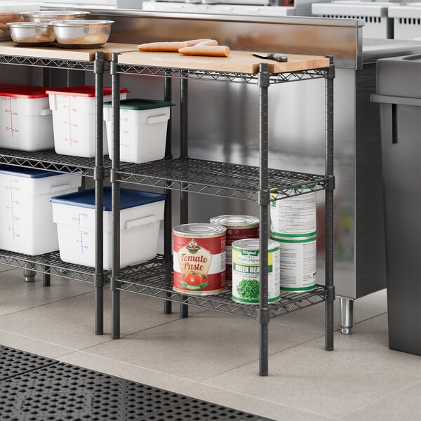 A kitchen with Regency black metal shelves holding food containers.