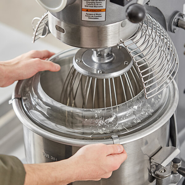 A person using an Avantco mixer with a splash cover.