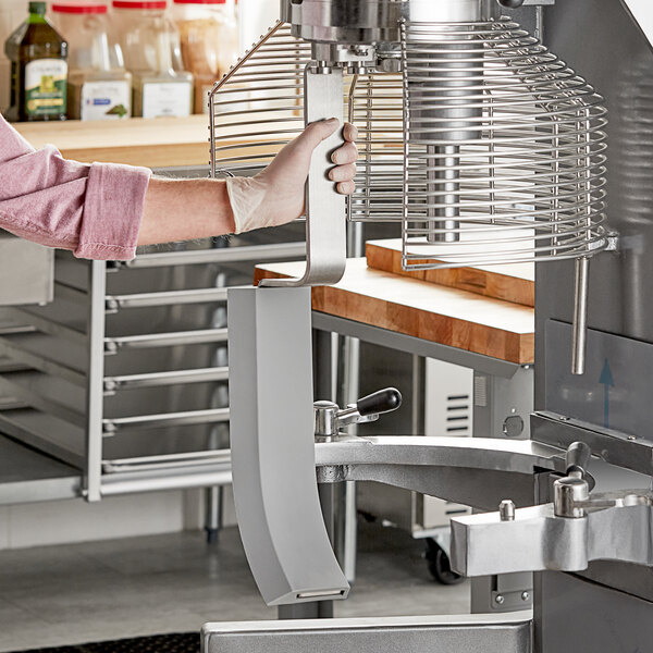 A woman using an Avantco bowl scraper attachment on an Avantco mixer.