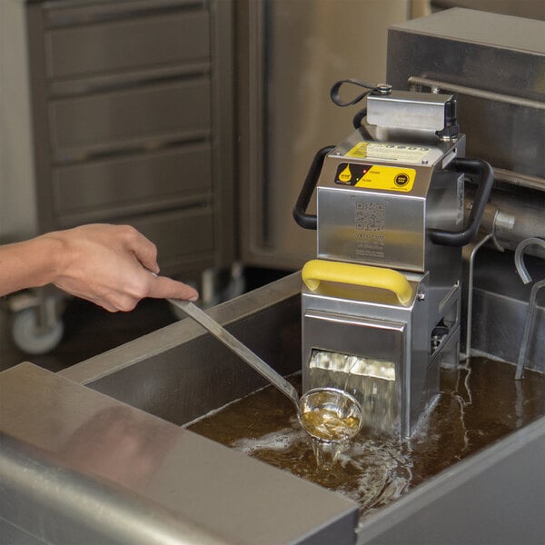 A person using a VITO fryer oil filtration machine to clean oil from a fryer.