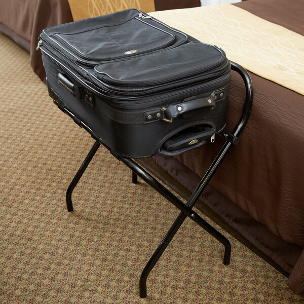 A black suitcase on a black Lancaster Table & Seating folding luggage rack.