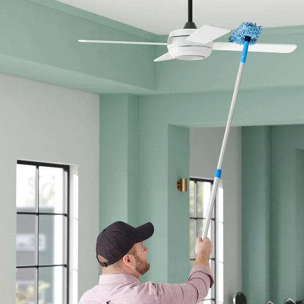 A man using a Lavex fan duster to clean a ceiling fan.