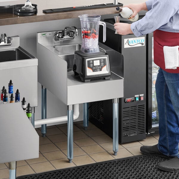 A man using a Regency blender station to pour a smoothie into a glass.