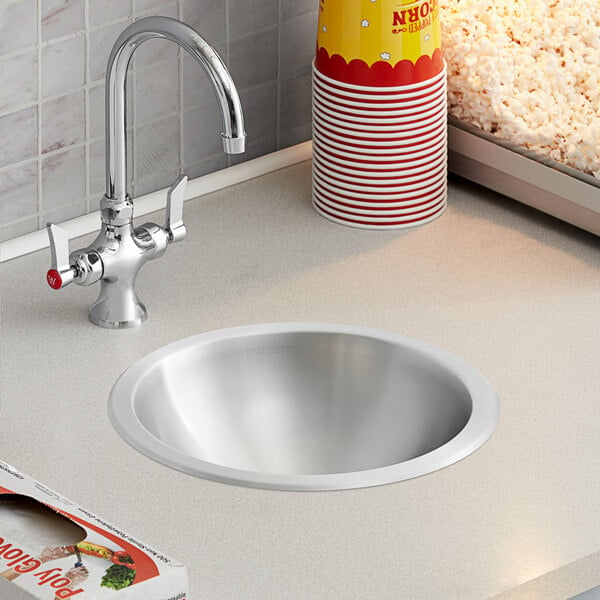 A Regency stainless steel drop-in sink with a bowl of popcorn on a counter.