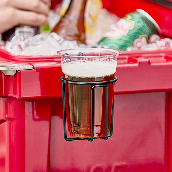 A hand holding a cup of beer in a CaterGator wire cup holder in a cooler.