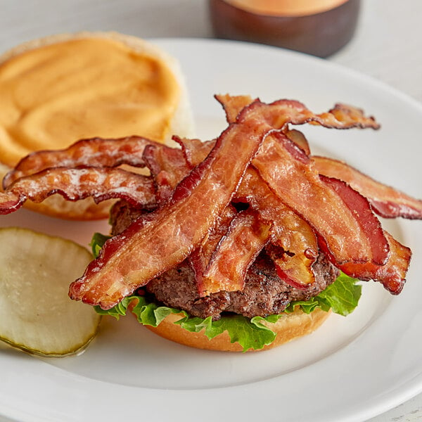 A plate with a Swift bacon burger and pickles.